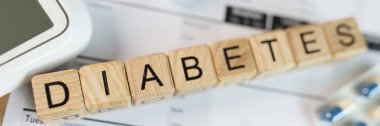 Tablodaki tahta küplere ilaç, glukometre ve kan şekeri testleri ile DIABETES harfleri. Diyabet, sağlık ve tedavi kavramı.