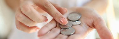 Close up of woman hand with silver coins. Female counting money in her hands. Inflation, small salary and poverty concept.