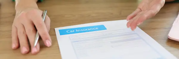Woman agent of insurance company offers to sign car insurance contract. Auto insurance form with pen on office desk and manager in background.
