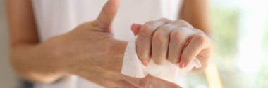 Woman cleans her hands close-up. Hand skin care, moisturizing hands with damp cloth.