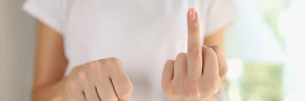 Woman showing fist and middle finger as fuck gesture. Bad expression, provocation and rude attitude.