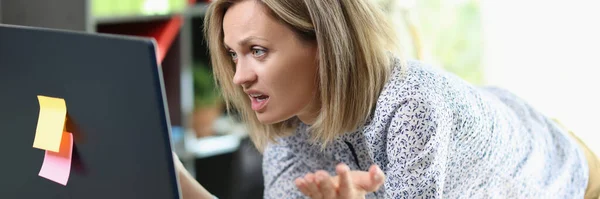 Frustrated business woman looking at computer screen in her office. Unhappy female manager shows upset face while working at computer.