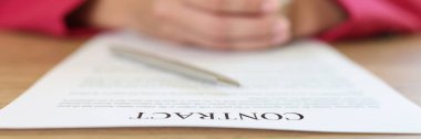 Female manager is sitting at work desk with contract agreement and pen. Closing deal, hiring employees and doing paperwork concept.