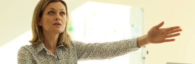 A tense woman in the office shows a index gesture, close-up. Stress in the workplace, overworked