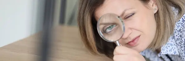 The woman leaning toward the shelf looks through the magnifying glass, close-up. Concept careful cleaning,