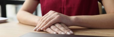 Female young hands are on the table in front of a closed laptop. Priorities at work, deadline