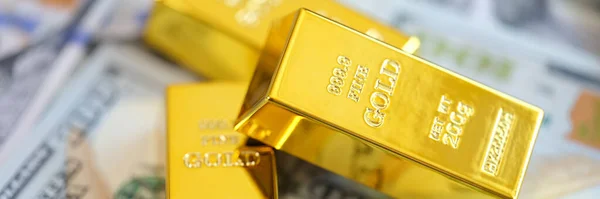 Close-up yellow gold bars lie on dollars. Financial wealth, cash exchange, business investment