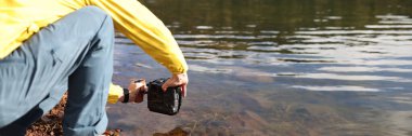 Close-up of man taking photo of lake using professional camera. Beauty of nature, natural landscape and travelling concept