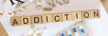 Addiction word collected with wooden cubes and medicines. Drug addict, obsession to pharmaceutical substances or narcotics or anxiety pills