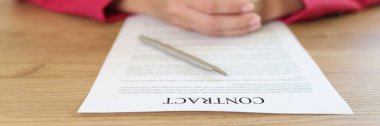 Close-up woman sitting at table in office, signing contract agreement. Signing and concluding business contracts