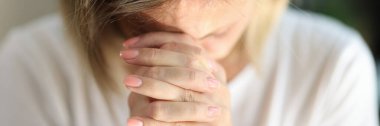 Close-up of praying woman folded hands, tilting head and prays. Faith, spirituality and religion concept