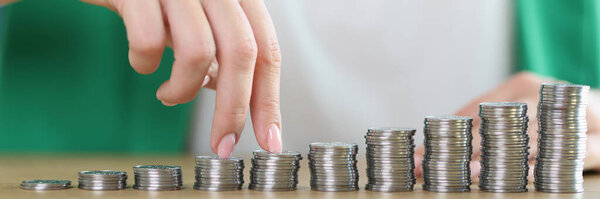 Close-up of woman fingers going up on bar chart of coins. Business growth, increase income, wealth and success concept