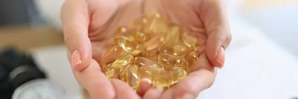 Close-up of doctor holding transparent yellow capsules in hands. Vitamin D. Healthy and medical concept