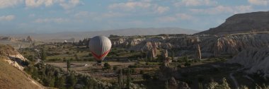 One hot air balloon over fairy chimneys and valley in Cappadocia, Turkey. Extreme touristic adventures and travel concept.