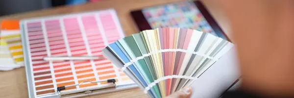 Designer advises his client to choose color from different samples in design studio. Close-up of woman manager talking about decorating house with her customer.
