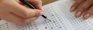 Female student answers test questions with pencil. Woman chooses correct answers in test paper. Study and exam concept.