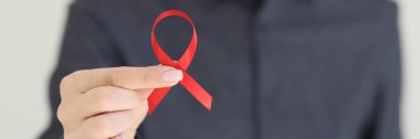 Kadının elinde AIDS 'e karşı verilen savaşı temsil eden kırmızı kurdele var. AIDS 'li insanlar ve kişilerle farkındalığın ve dayanışmanın sembolü