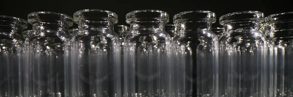 Empty glass vials for vaccines stand in row on dark background. Professional glassware for medical purposes and laboratory investigations