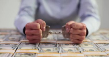 Kadının elleri kelepçeli ve masada bir sürü dolar var. Yolsuzluk suçlarına rüşvet ve tutuklama