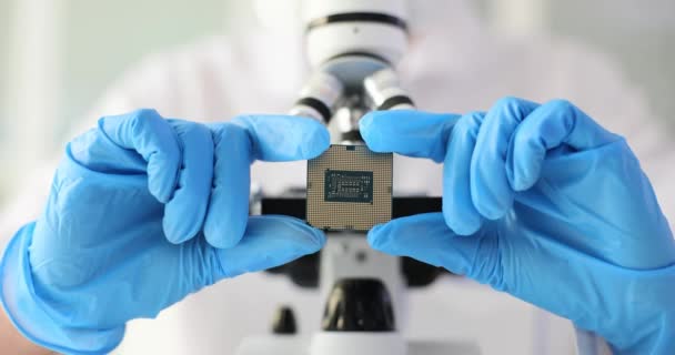 戴手套的电子工程师在显微镜的背景下保持着微电路 检查电脑芯片及电子及科技 — 图库视频影像
