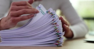 İş kadını iş yerindeki klasörde belge ya da bilgi arıyor. İş raporu kağıdı veya tamamlanmamış belge yığınlarına ofisteki şarjörlerle ulaşılır