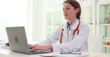 Kadın doktor dizüstü bilgisayarda çalışıyor ve tıp hastanesinde kapanıyor. Tıp işçilerinin çalışma günü bitti.
