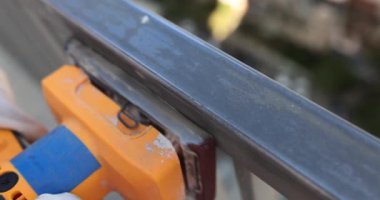 Usta terasta ya da balkonda makineyle metal öğütüyor. Metal borular boyaya hazırlanıyor