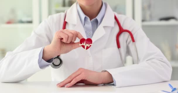 心臓の赤いアイコンを手で閉じ込めている心臓医師 医師は心臓のシンボルと心臓病の治療を示しています — ストック動画