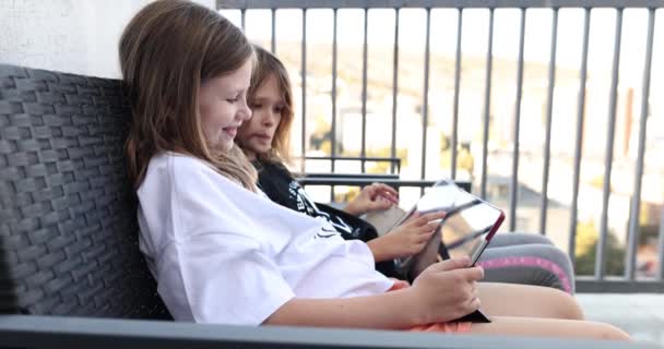 Dwie Dziewczynki Siostry Siedzą Patio Bawią Się Tabletem Dzieci Aplikacje — Wideo stockowe