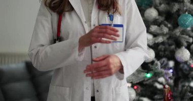 Steteskopu ve Noel ağacı olan kendinden emin bir kadın doktor. Tıbbi Yeni Yıl kurumsal partisi
