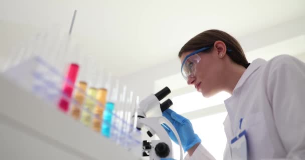 Bióloga Científica Química Sienta Laboratorio Mesa Examina Líquidos Bajo Microscopio — Vídeos de Stock