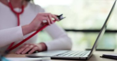 Kadın dizüstü bilgisayara steteskop koyuyor. Teletıp ve uzaktan tıbbi bakım