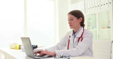 Uzaktan tıbbi konsültasyon için dizüstü bilgisayar kullanan ciddi genç bir bayan doktor. Çevrimiçi sohbetteki kadın tıbbi uzman danışman hasta