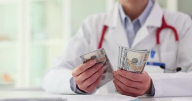 Kadın doktor kendinden emin ve klinikte dolar sayıyor. Tıp ve sağlık sektöründen para kazanmak
