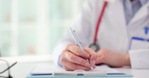 女性医師はペンを保持し 患者のチャートのクローズアップを書きます 患者訪問 医療費と保険をチェックする — ストック動画