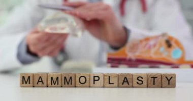 Plastik cerrah silikon implantı gösteriyor ve hastaya mammoplasti diyor. Göğüs büyütme ve kaldırma ameliyatı