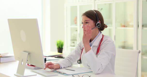 ヘッドセットを着用している女性医師は ウェブカムを介して患者とオンライン相談を行います 病院のビデオ通話で話すヘッドフォンを身に着けているセラピスト — ストック動画