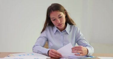 Kadın ofis çalışanı tamamlanmamış belgeleri ofis masasına ve bir yığın iş belgesine serer. İş belgeleri inceleniyor