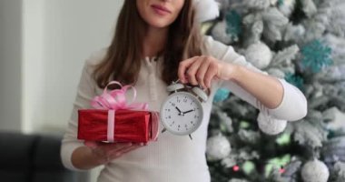 Kadının elinde hediye kutusu ve çalar saat var. Yeni yıl ve Noel hediyeleri almak için zaman ve planlama