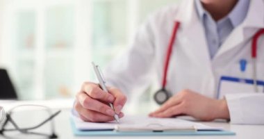 Terapistin elleri tıbbi kayıtlarda kalemle not alır. Doktor notları ve tıbbi belgeleri dolduruyorum.