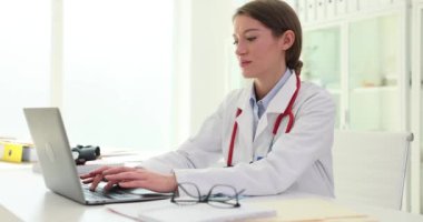Dizüstü bilgisayarda çalışan ve klavyede daktilo yazan kadın hemşire. Tıp çalışanı bilgisayara reçete yazar.