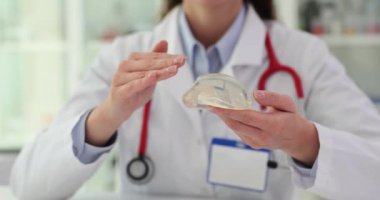 Uzman doktor silikon ve tuz implantı modelleri gösteriyor. Yüksek kalite yumuşak implant seçiliyor