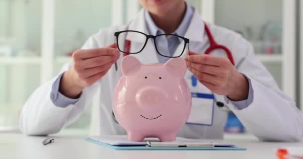 医生把眼镜放在诊所的储蓄罐上 医疗储蓄和医疗保险的成本 — 图库视频影像