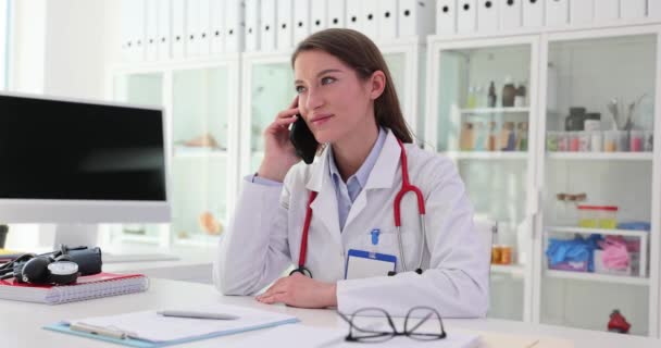Γυναίκα Γιατρός Μιλάει Στο Κινητό Τηλέφωνο Στο Ιατρικό Γραφείο Σίγουρος — Αρχείο Βίντεο