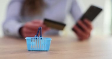 Kredi kartı, akıllı telefon ve alışveriş arabası tutan kadın eller. Ani uzaktan ödeme ya da hızlı uzaktan para transferleri yap