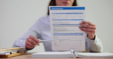 Kadın ajan elinde sigorta başvuru formu tutuyor. Şirket ofisindeki sigorta acentesi sözleşmeli kayıt hizmetleri sunuyor