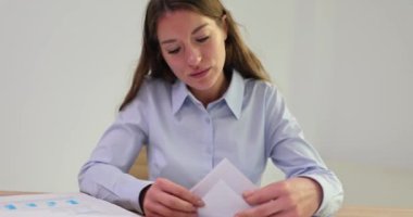 Kadın ofis çalışanı tamamlanmamış belgeleri ofis masasına ve bir yığın iş belgesine serer. Mali rapor ve iş belgeleriyle çalışan muhasebeci veya CEO