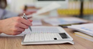 Şirket gelirlerini ve bütçesini kontrol etmek için hesap makinesi kullanan iş kadınlarının yakınlaşması. Aylık giderleri hesaplayan iş kadını