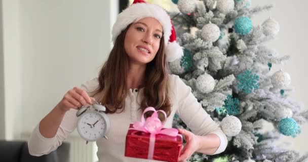 新年のための時計と贈り物を保持する美しい若い女性 クリスマスと新年の贈り物を選択する時間 — ストック動画