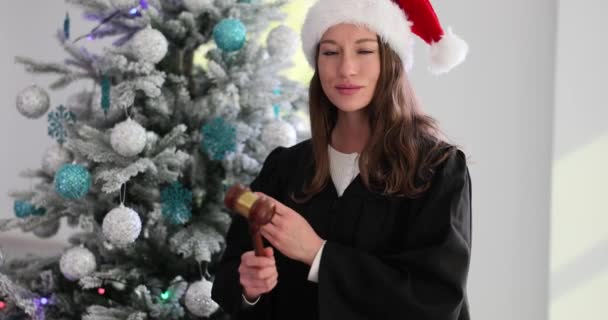 Kvinnlig Domare Santa Claus Hatt Håller Klubban Mot Bakgrund Julgran — Stockvideo